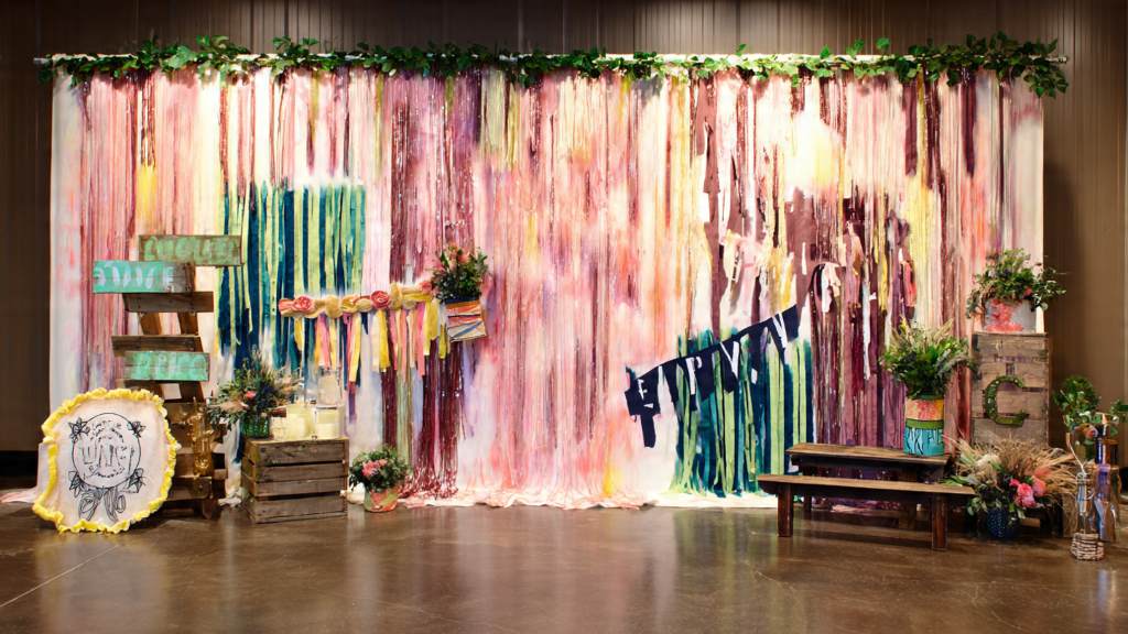 Fabric banner backdrop featuring painted slogans and fringe for spirited photos.